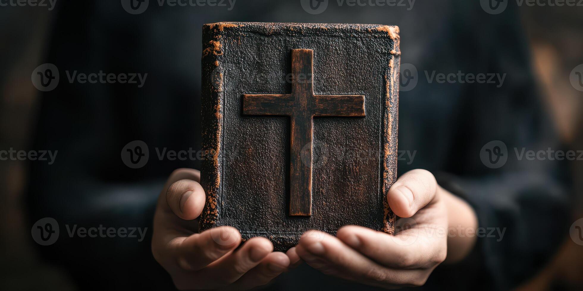 A person holding a weathered book with a cross symbol in a dimly lit space, conveying a sense of reverence and spirituality photo