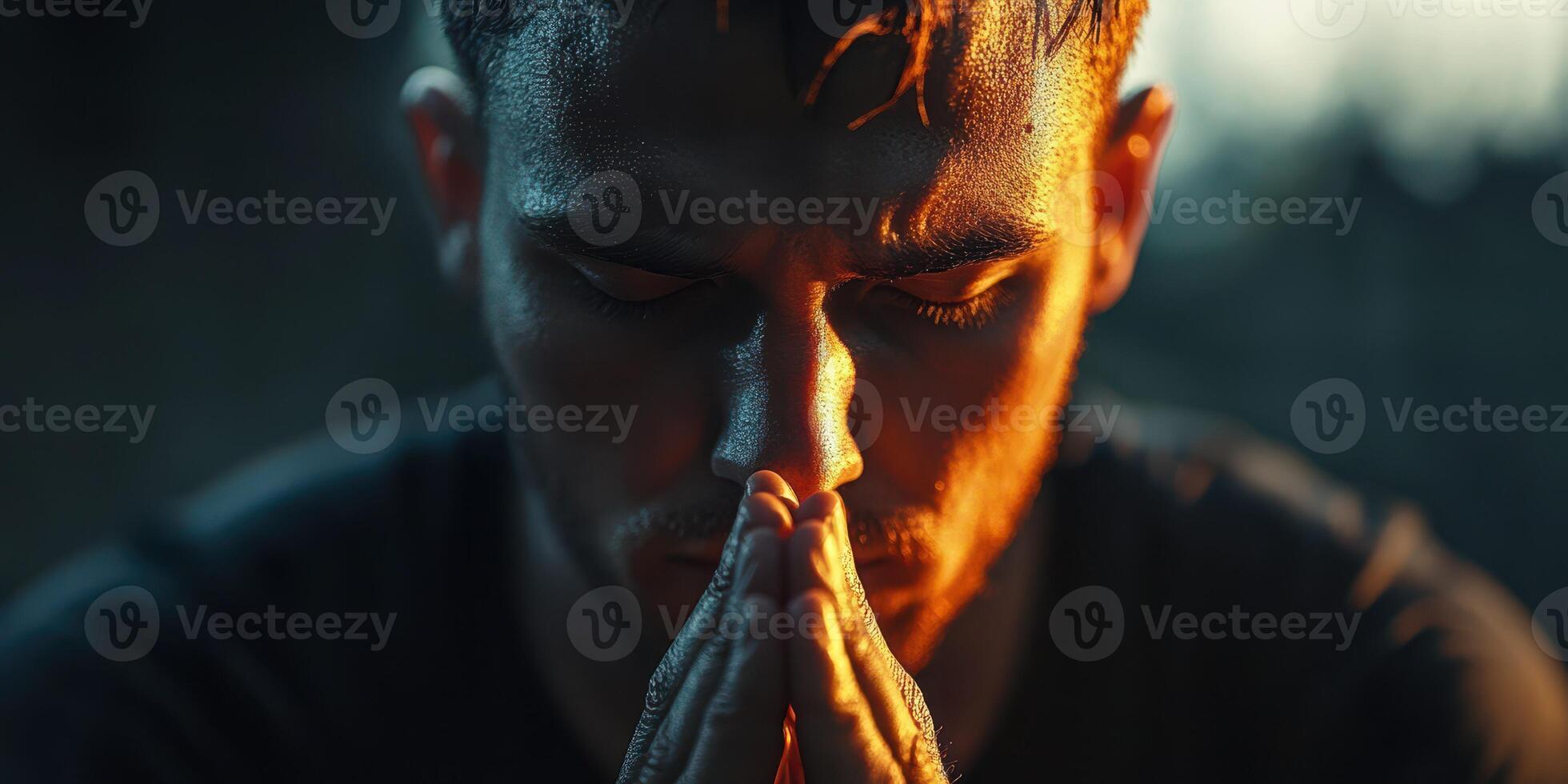Man in deep concentration with hands clasped near face under warm lighting during evening hours photo