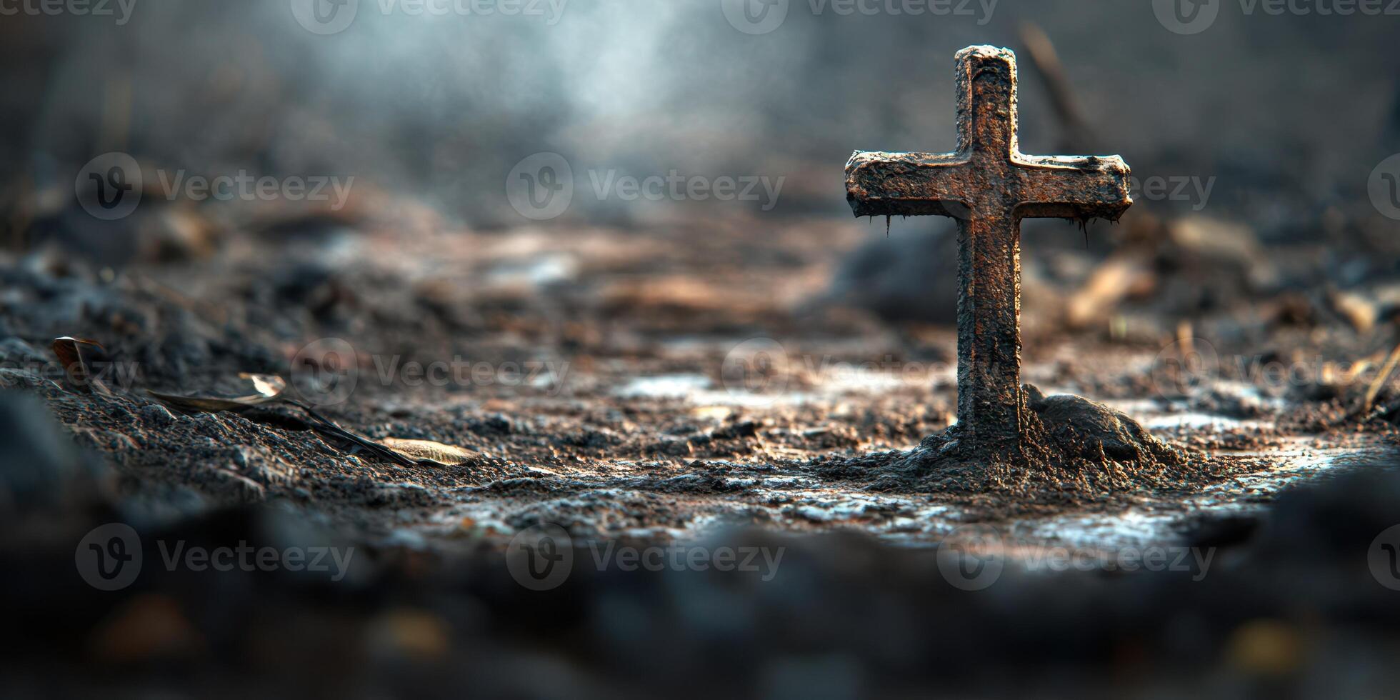 Cross standing alone in a desolate, misty landscape with uneven terrain and scattered leaves photo