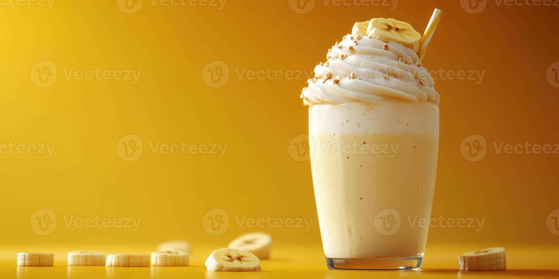 Creamy banana milkshake served in a tall glass with whipped cream and banana slice on top against a vibrant yellow background photo