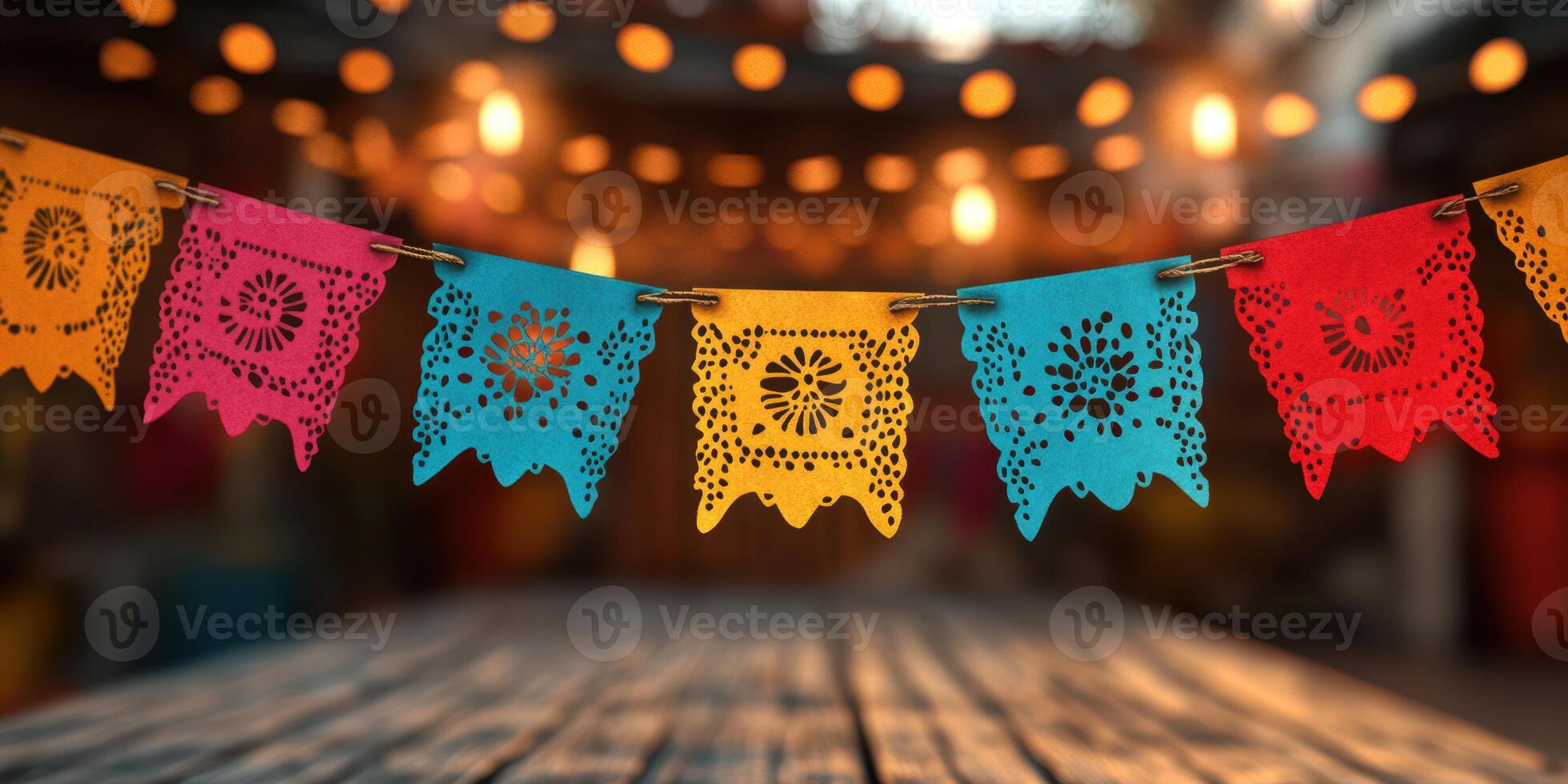Colorful papel picado banners hanging over a wooden table in a lively festive setting with warm lights photo