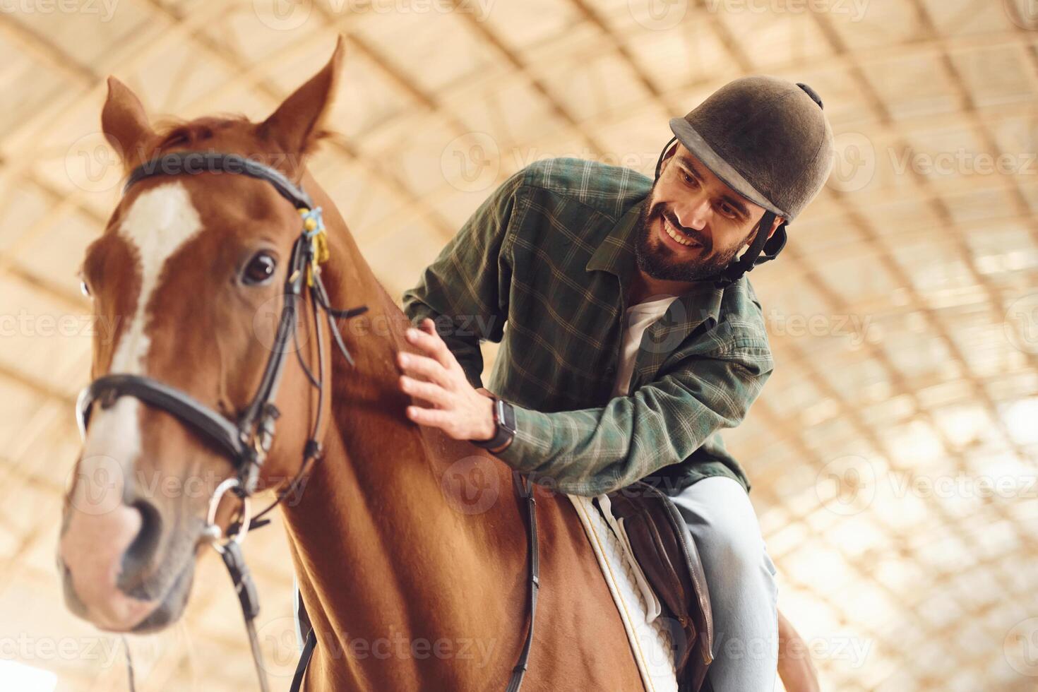 Sitting in the saddle.. Young ,man with a horse is in the hangar photo