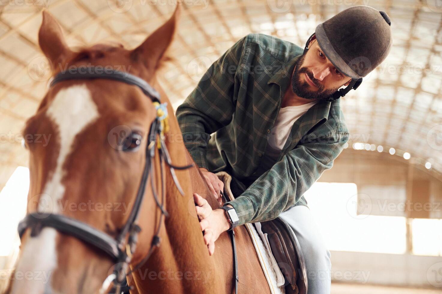 Jockey is in the saddle. Young man with, a horse is in the hangar photo