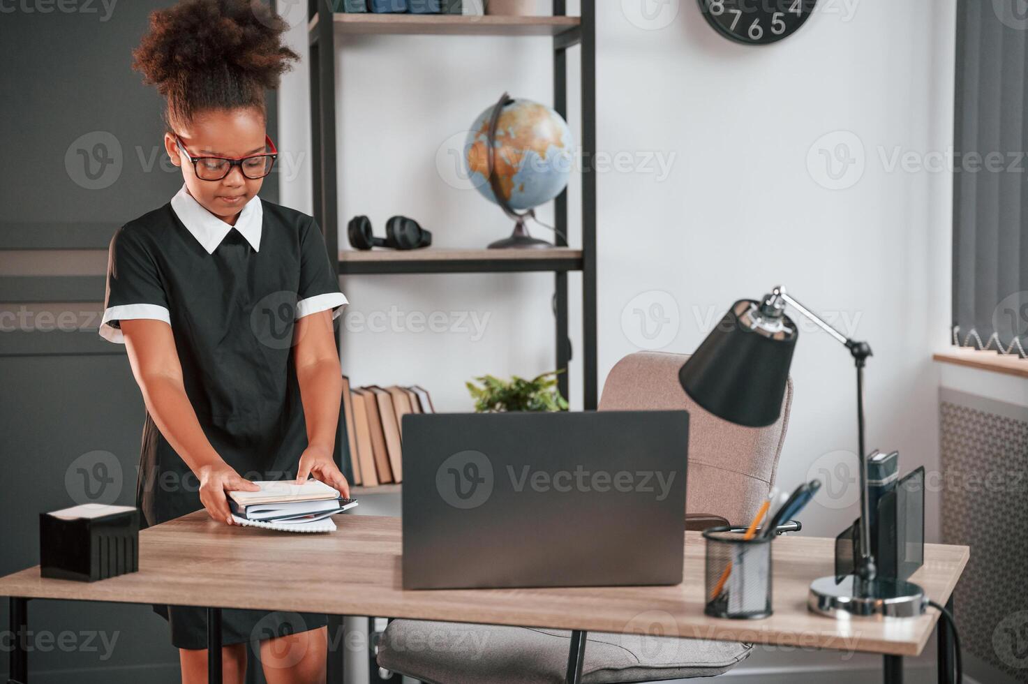 Cute ,little girl in school uniform is standing indoors in domestic room photo