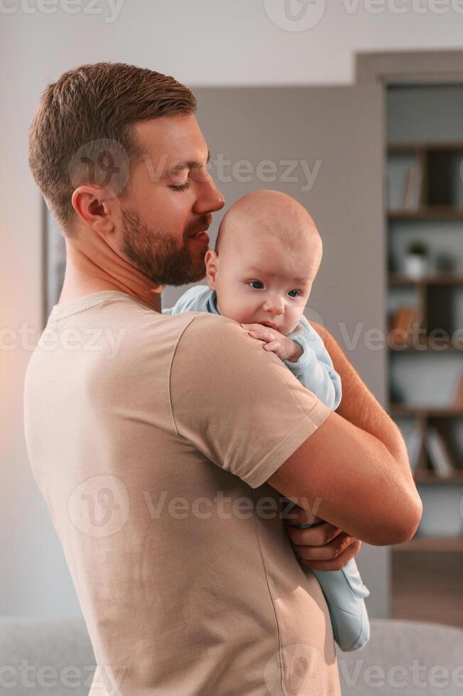Holding, kid in hands. Father with his newborn baby is indoors. Conception of single dad photo