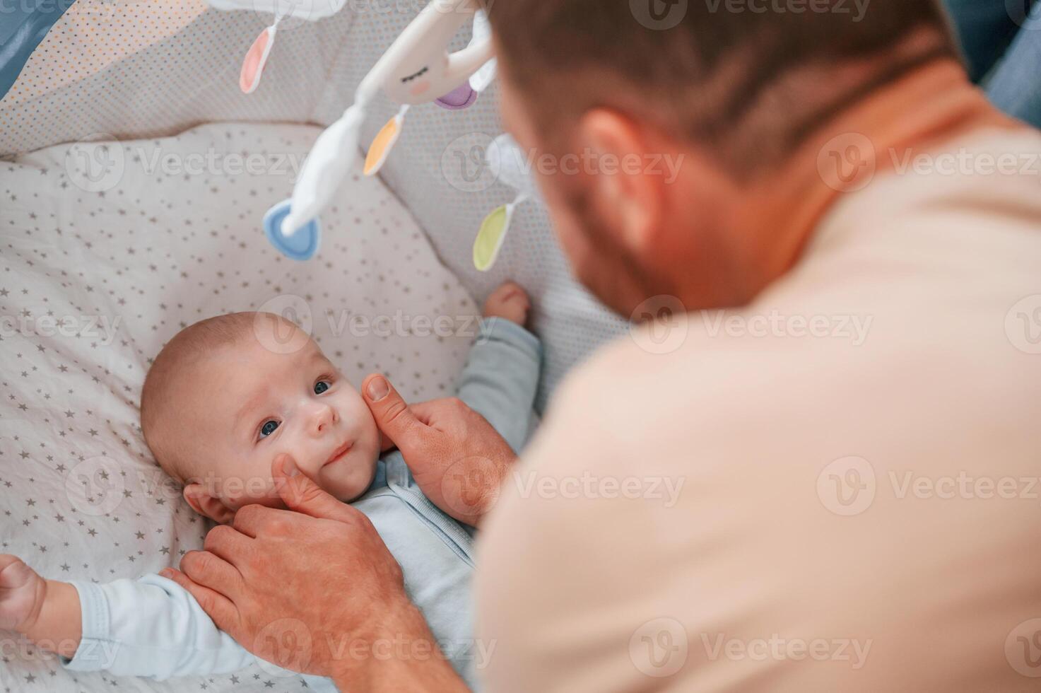 Newborn, baby is in the cradle.. Father is indoors. Conception of single dad photo