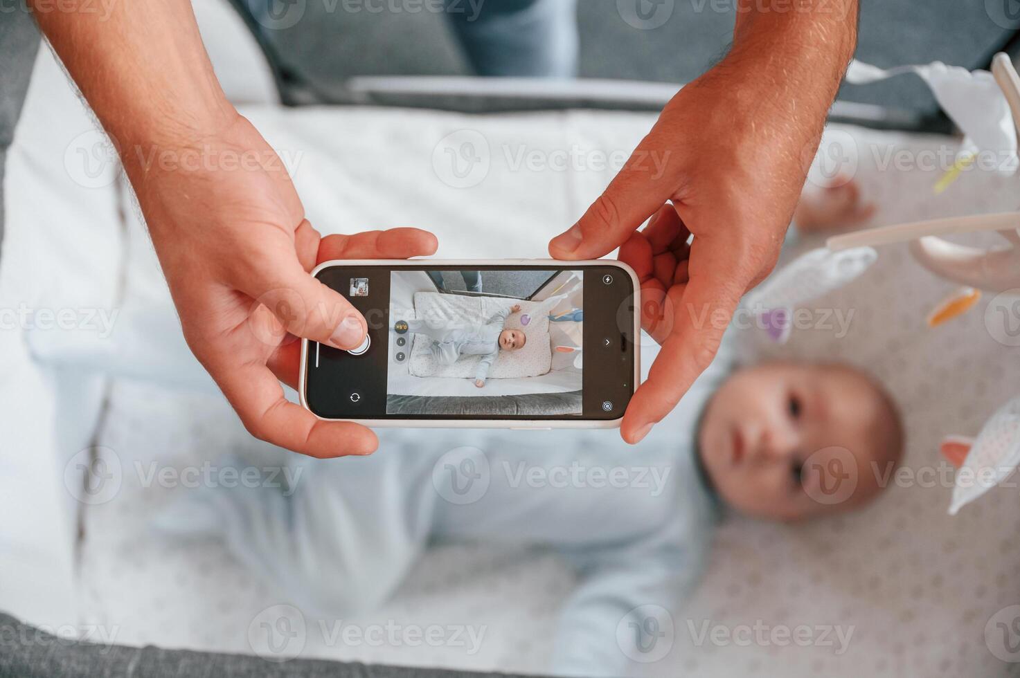 Taking picture by ,smartphone. Father with his newborn baby is indoors. Conception of single dad photo