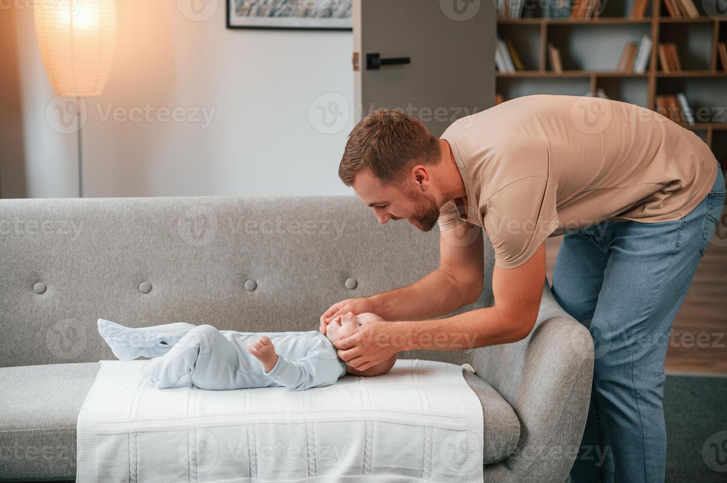 Taking ,care of newborn baby ,that is on the sofa. Father is indoors. Conception of single dad photo