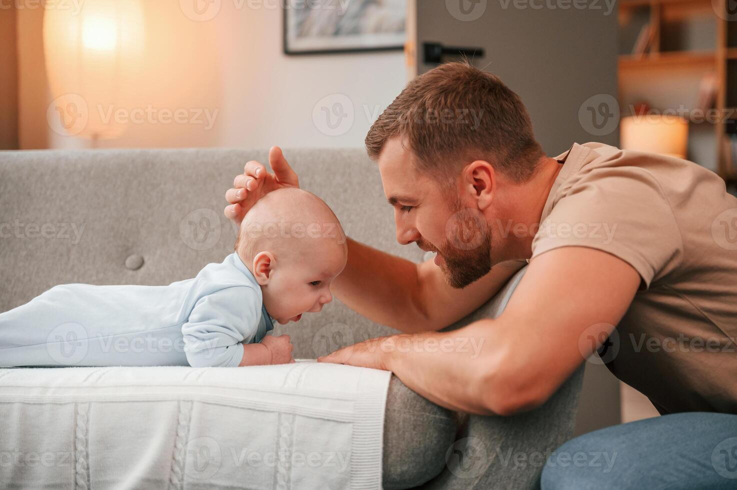 Strokes his head. Father with his newborn baby is indoors. Conception of single dad photo