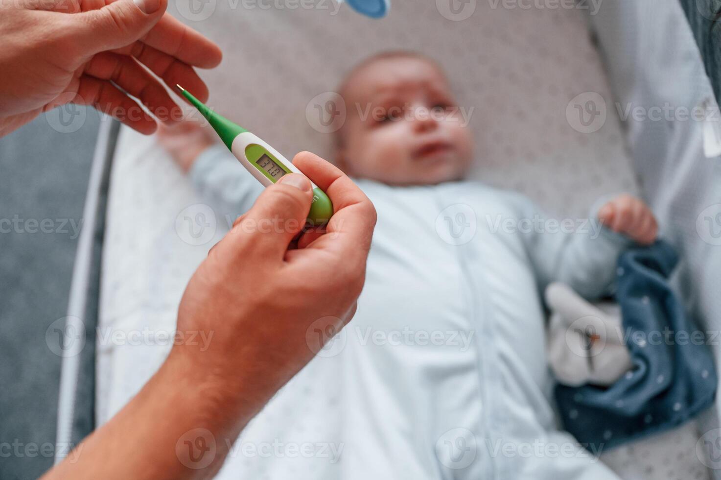 Holding, thermometer, kid in the cradle.. Father with his newborn baby is indoors. Conception of single dad photo