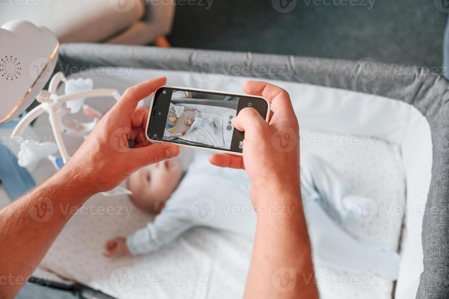 Taking picture by smartphone. Father with his newborn baby is indoors. Conception of single dad. photo