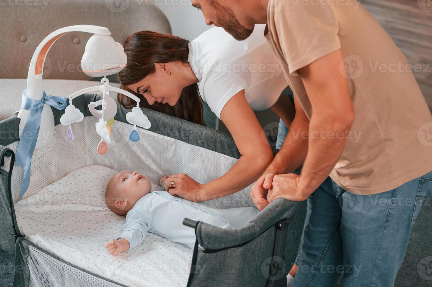 Looks down at the kids. .Lovely couple ,taking care of newborn baby indoors at domestic room photo