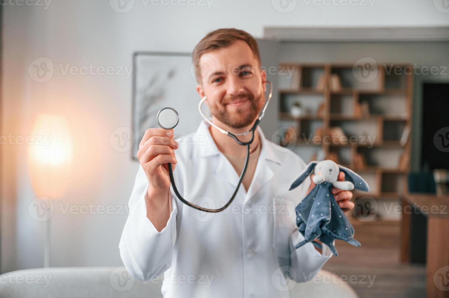 Portrait of ,male doctor in white coat that holding stethoscope with toy photo