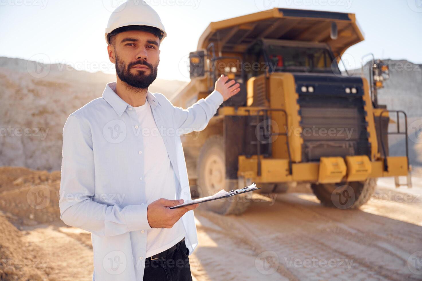 Smart, person is with ,documents in hands. Man in uniform is working in the quarry at daytime photo