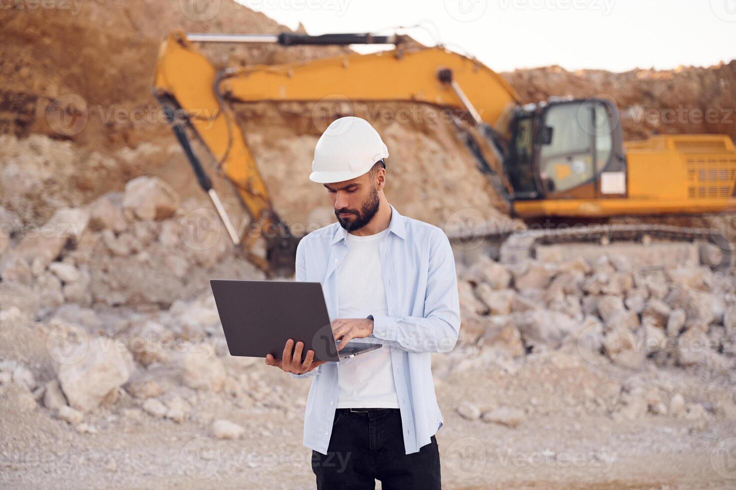 Using laptop. Man in uniform is working ,in the quarry at daytime photo