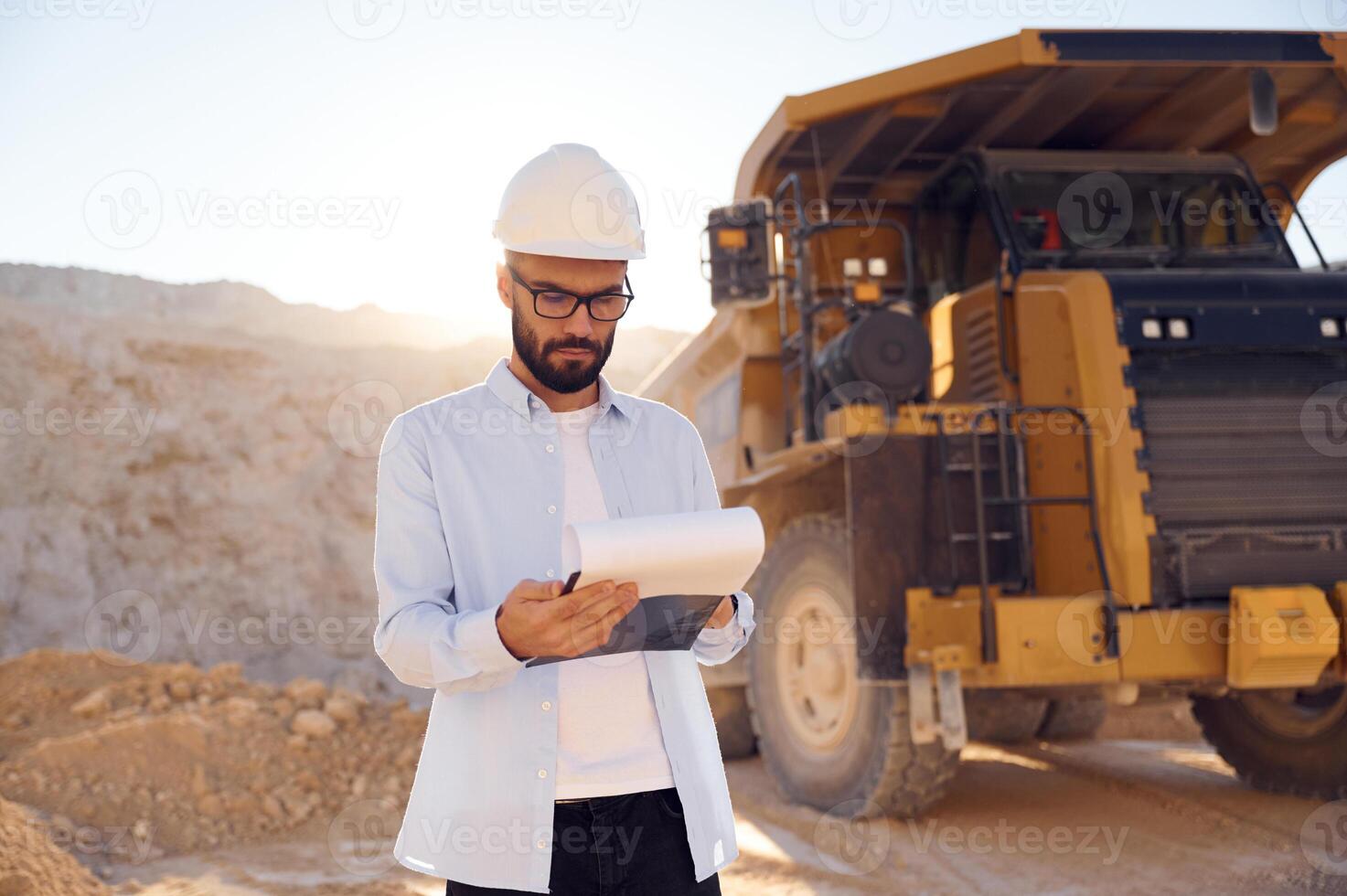 Smart, man in glasses, and in uniform is working in the quarry at daytime photo