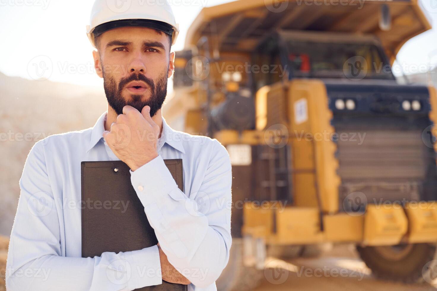 Smart ,person is with documents in hands. Man in uniform is working in the quarry at daytime photo