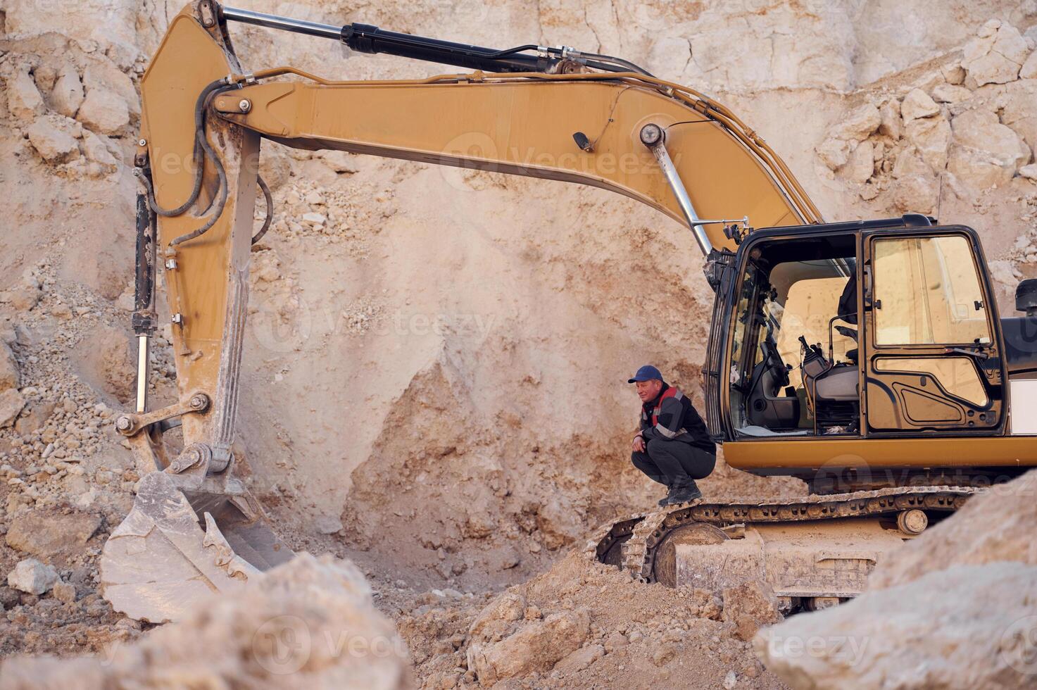 Middle, aged man is with excavator in the quarry at daytime photo