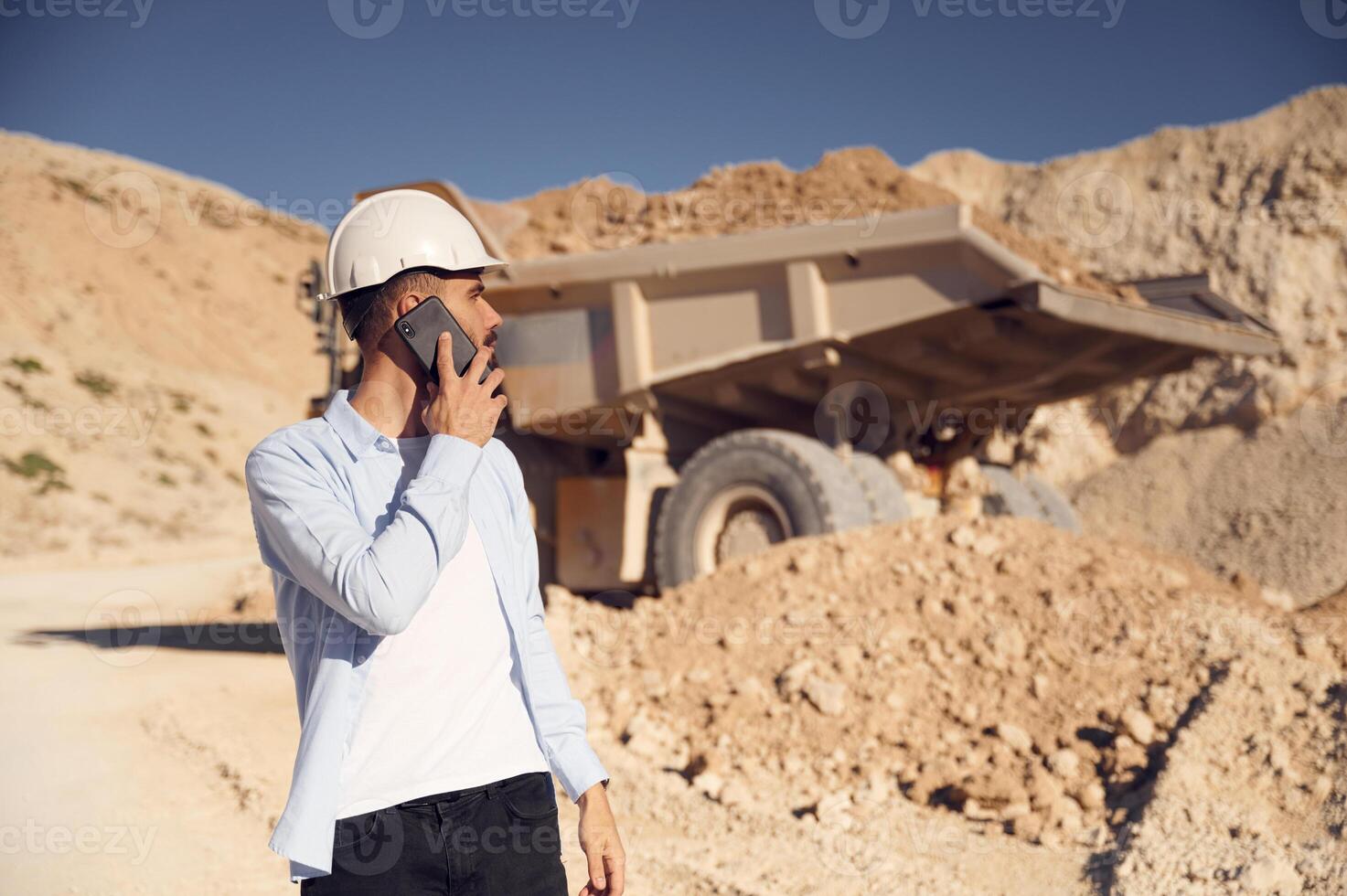 Business conversation by phone. Man in uniform is,working in the quarry at daytime photo