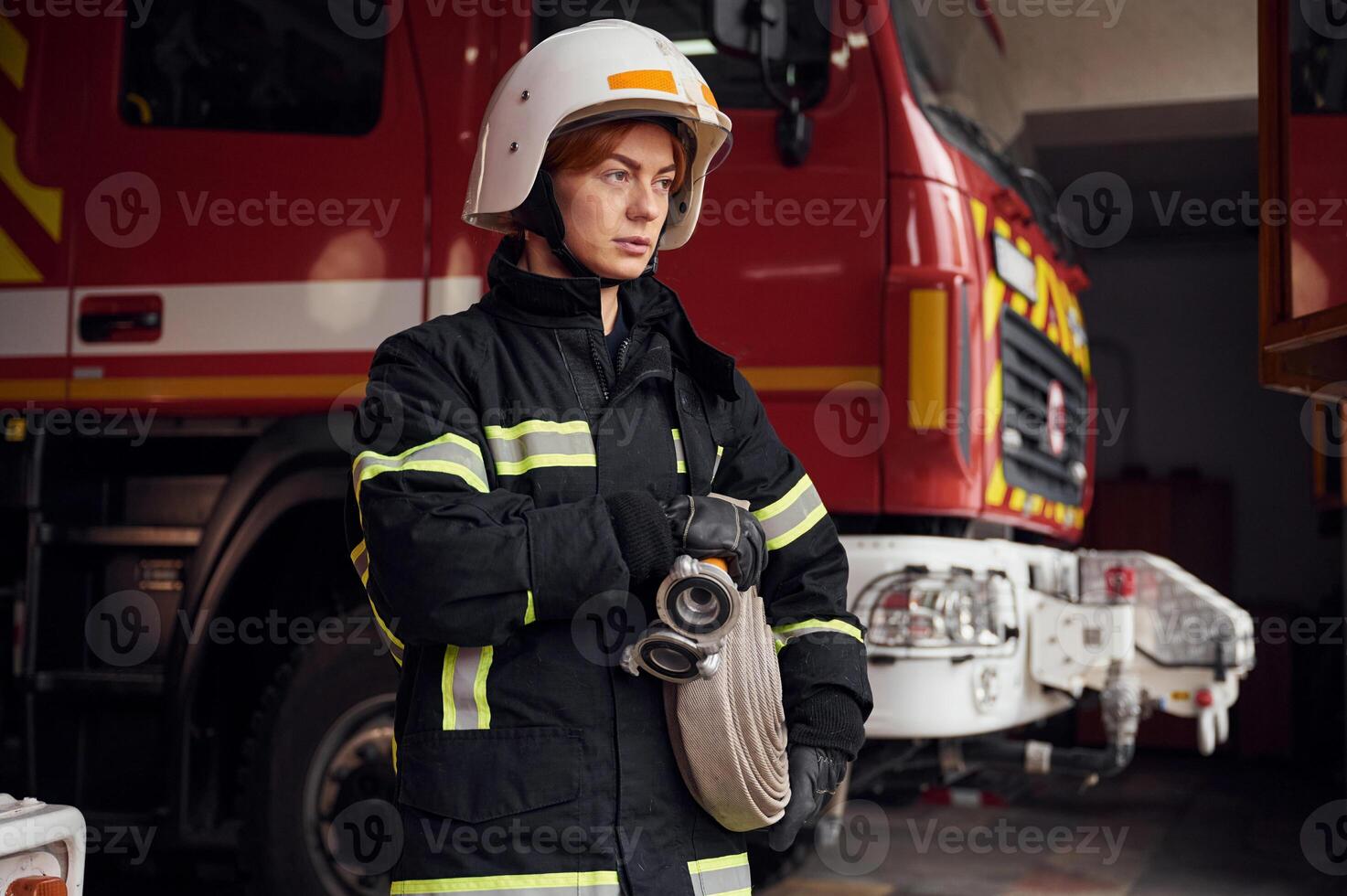 Grey ,colored fire hose is in the hands. Woman in uniform is at work in department photo