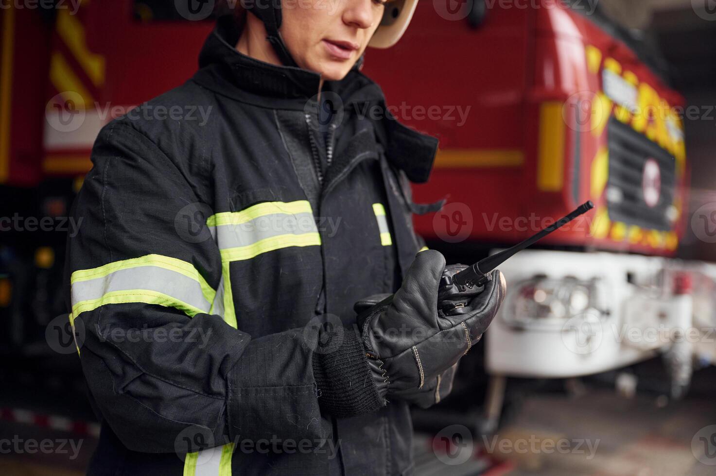 Using ,radio transmitter. Woman firefighter in uniform is at work in department photo