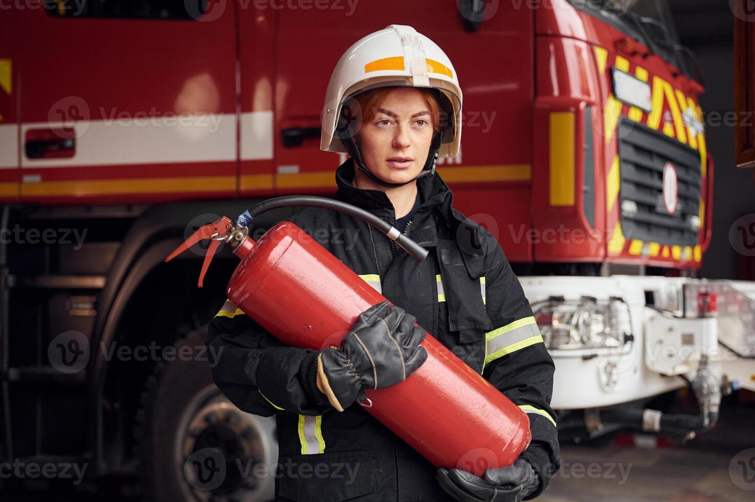 Fire extinguisher in in the hands of woman that is in uniform at work in department photo