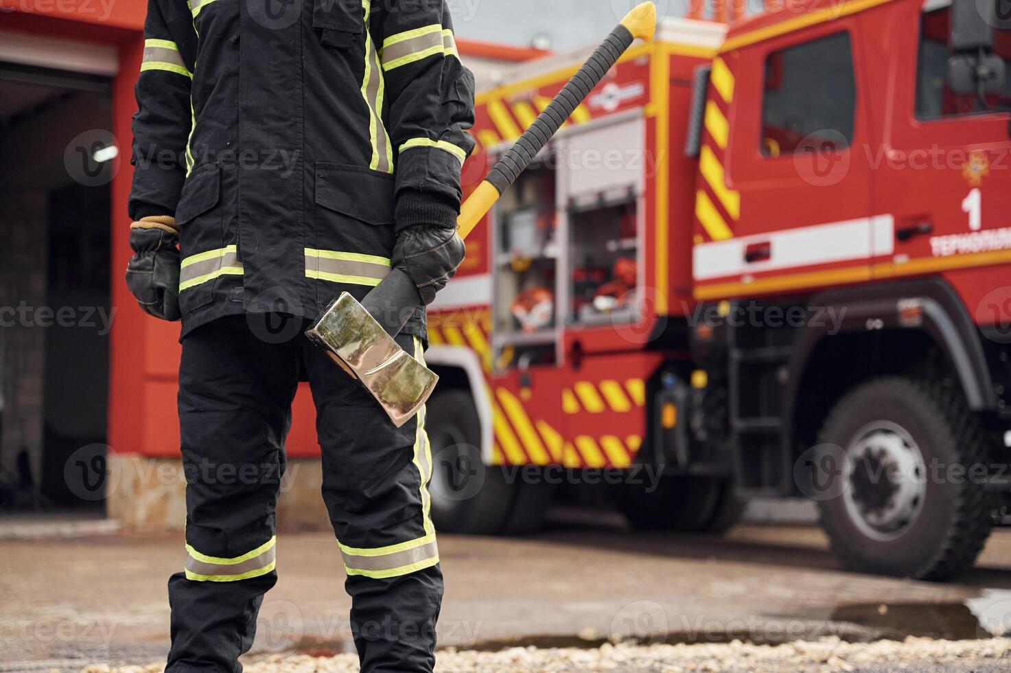 In uniform with axe in hands. Woman firefighter is at work in department photo