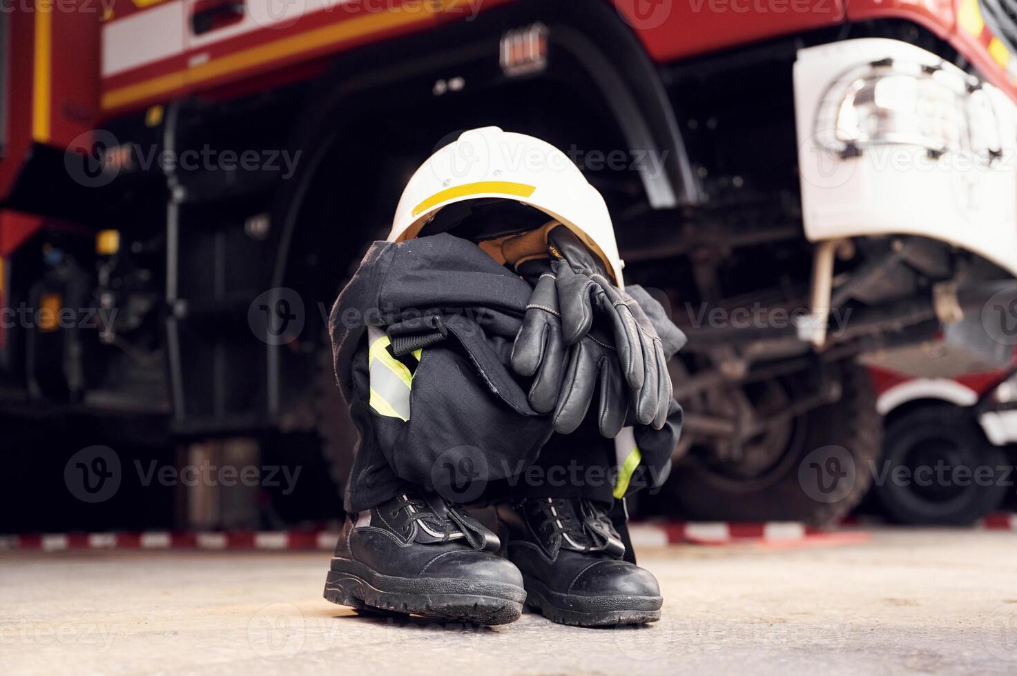 Close ,up view of firefighter's hat, gloves, jacket, pants and shoes. With big vehicle photo