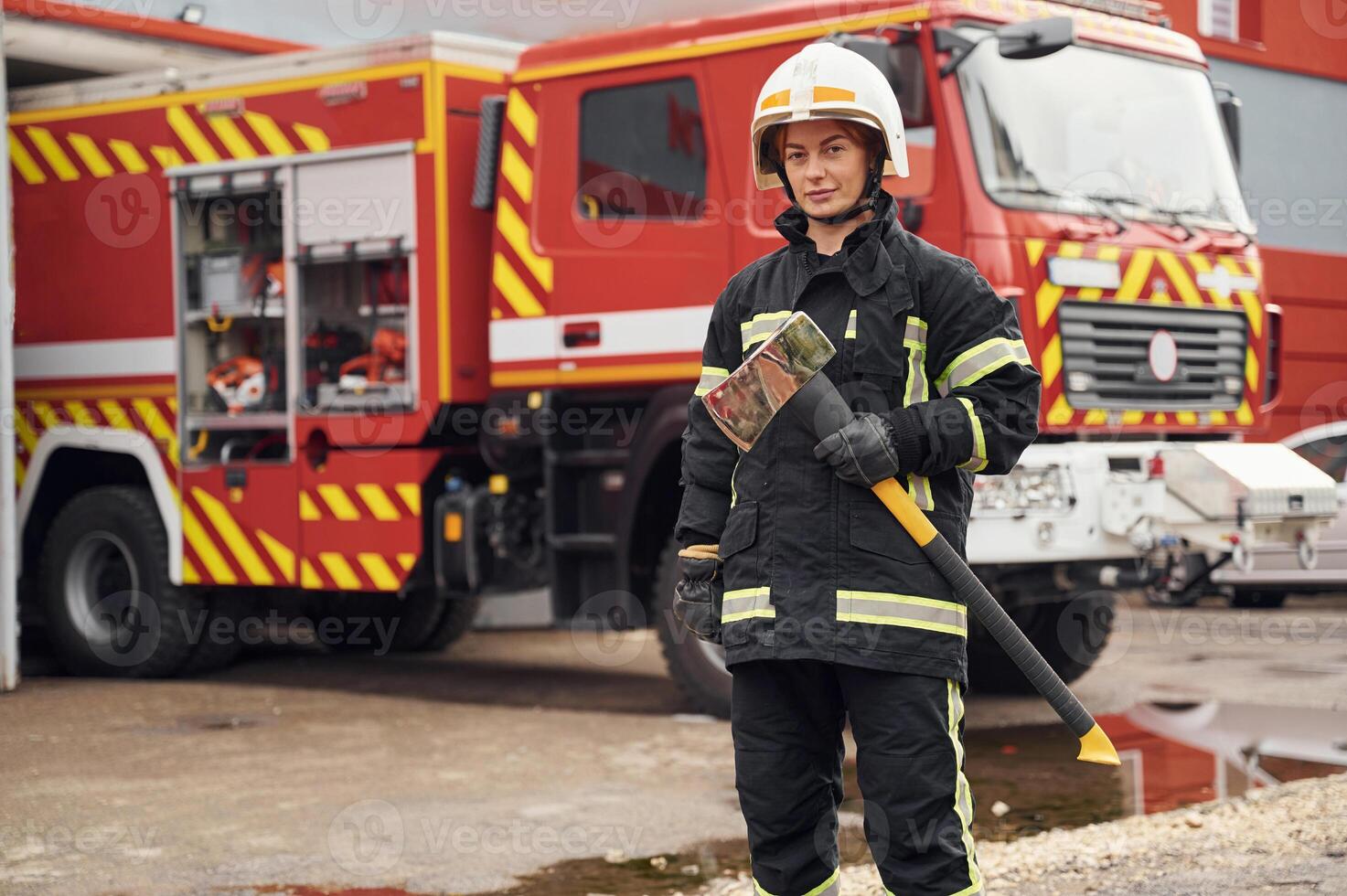 In, uniform with axe in hands. Woman firefighter is at work in department photo