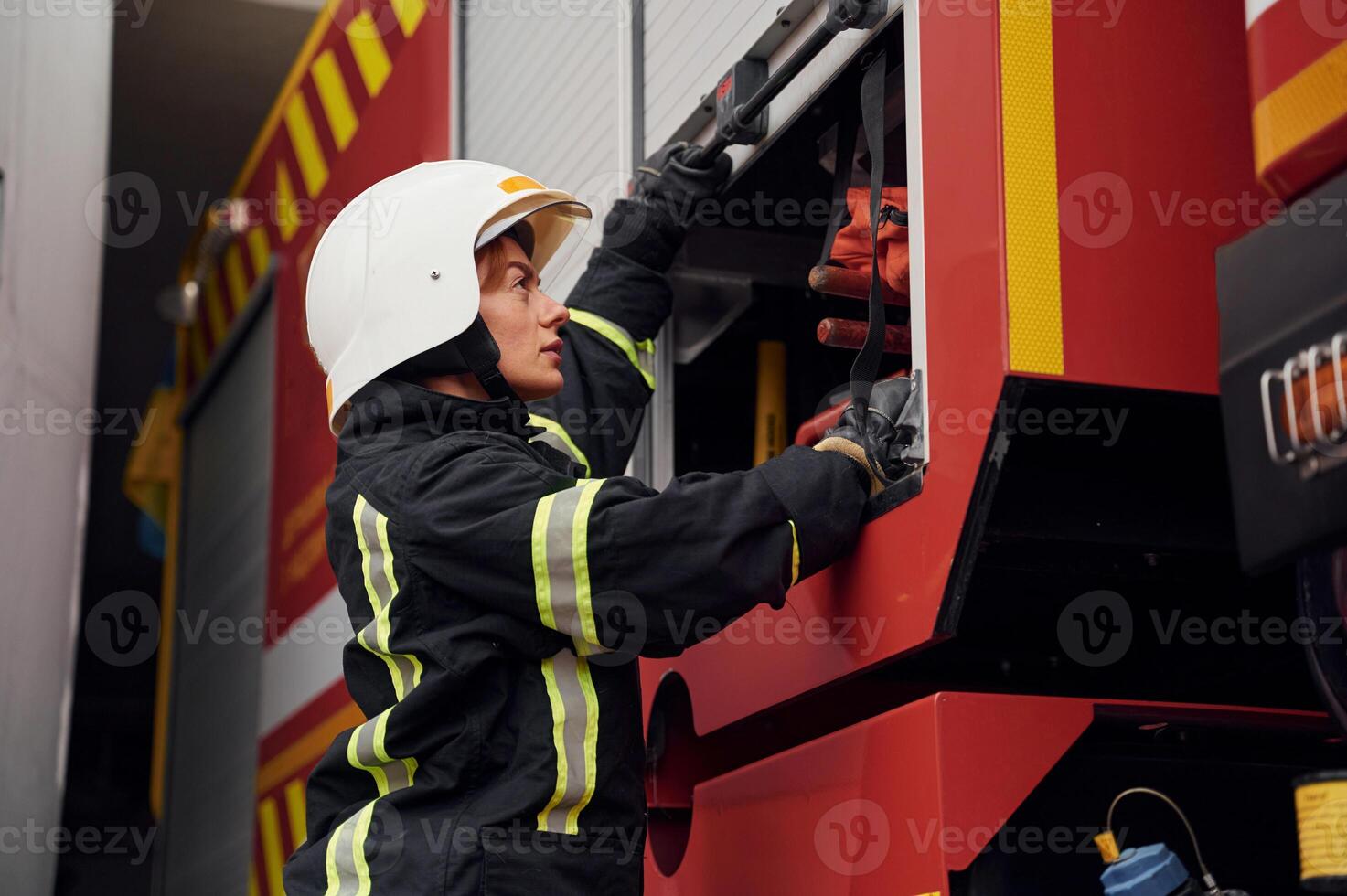 Taking ,equipment from the truck.. Woman firefighter in uniform is at work in department photo