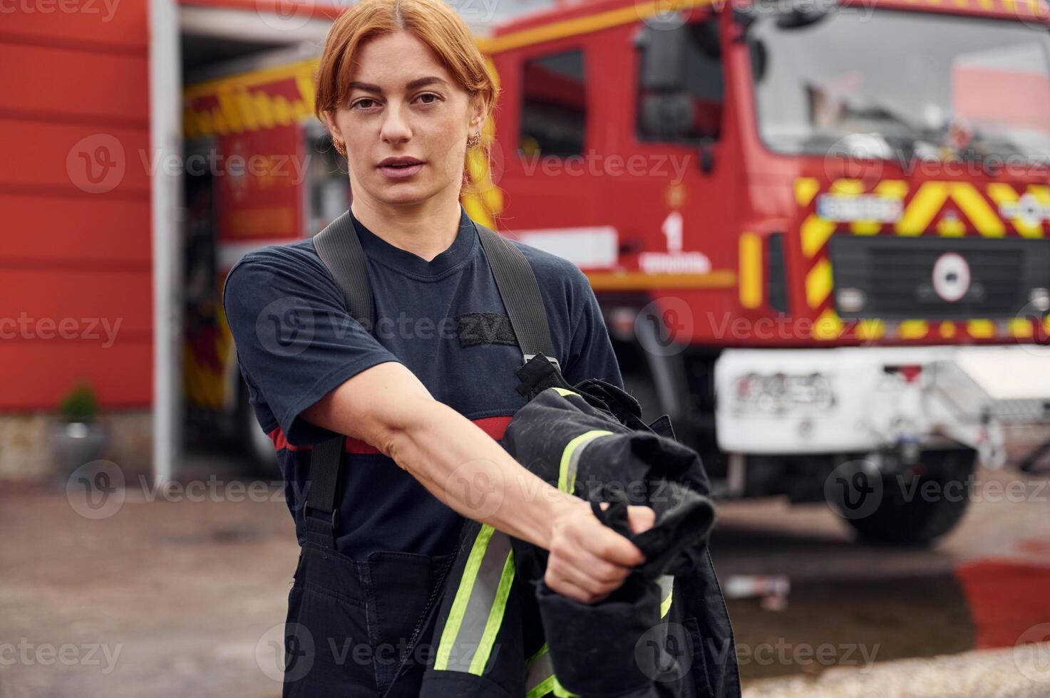 Taking off the protective clothes. Woman ,firefighter in uniform is at work in department photo