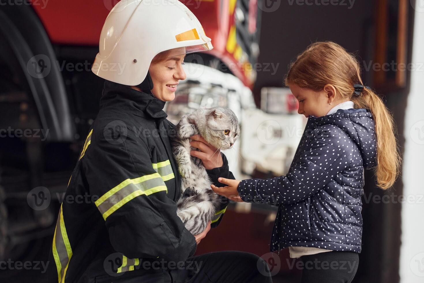 Rescued scottish fold cat.. Firefighter woman in uniform is with a little girl photo