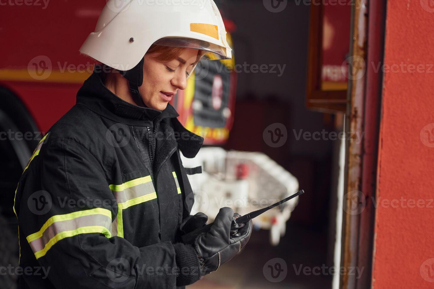 Using radio transmitter. .Woman firefighter in uniform is at work in department photo