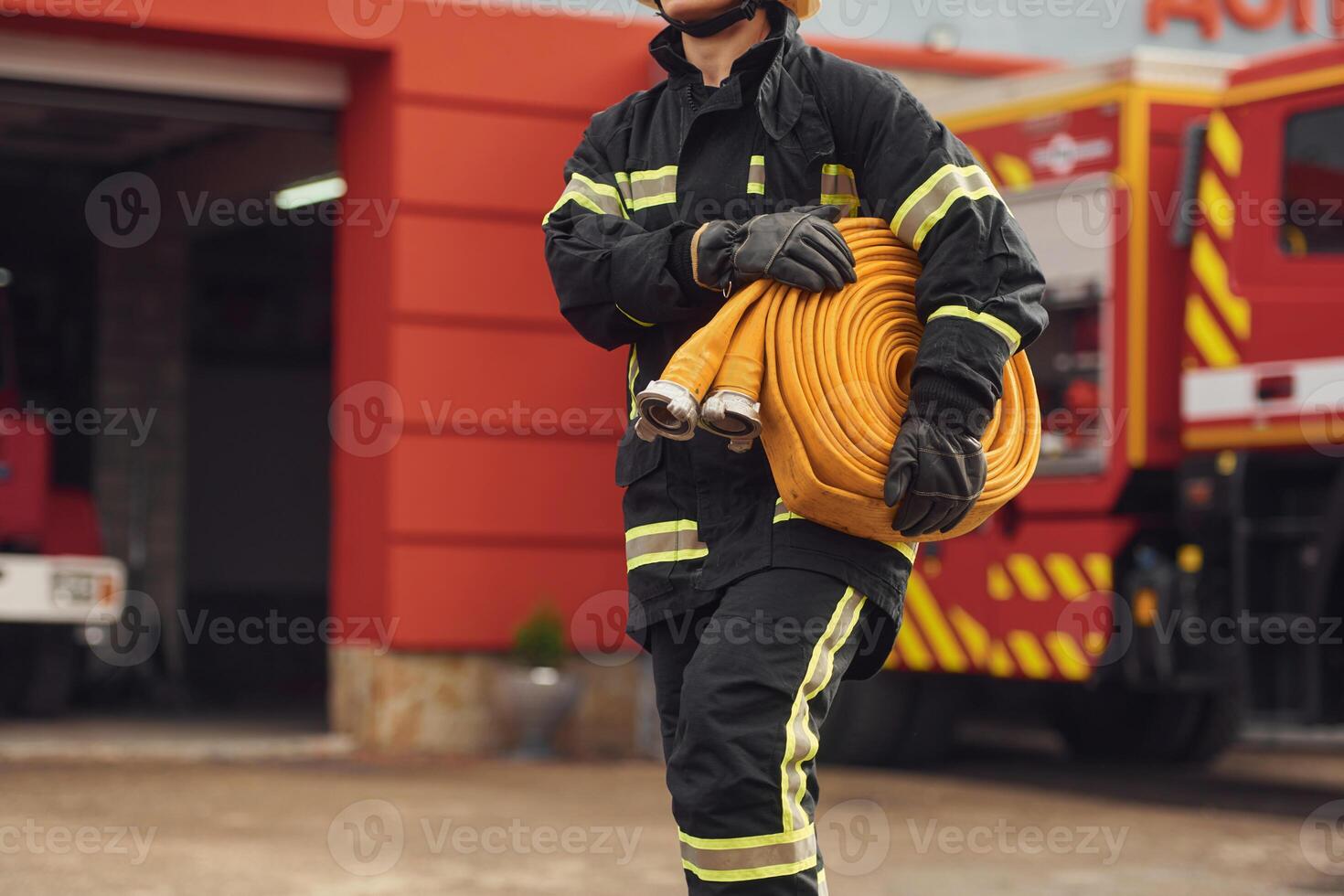 With fire hose in hands. Woman ,in uniform is at work in department photo