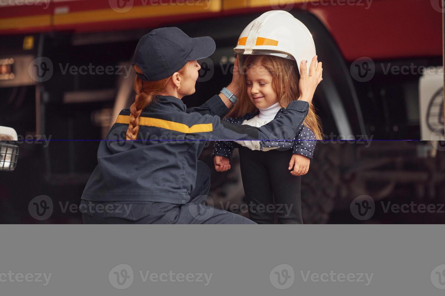 Wearing, the helmet. Firefighter woman in uniform is with a little girl photo
