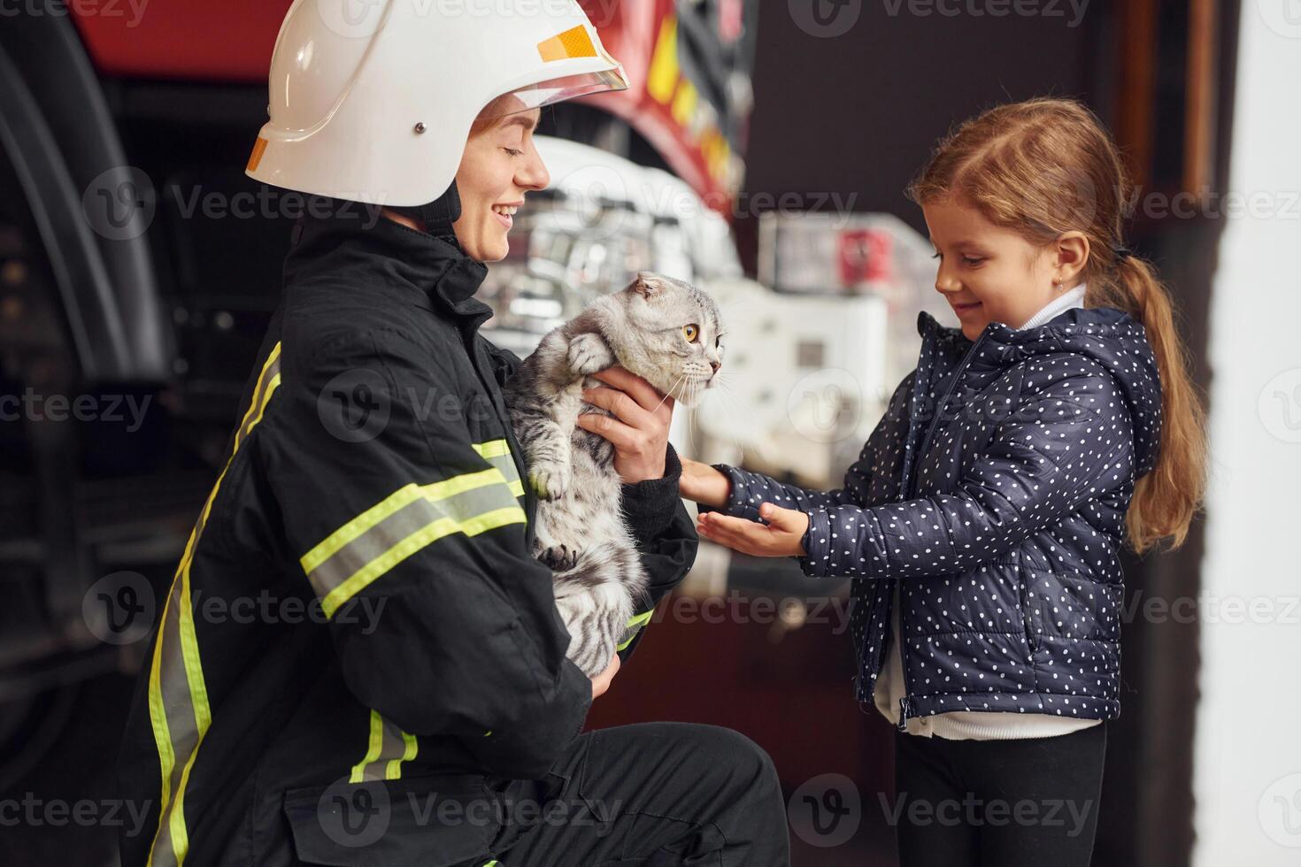 Rescued ,scottish fold cat. Firefighter woman i,n uniform is with a little girl photo