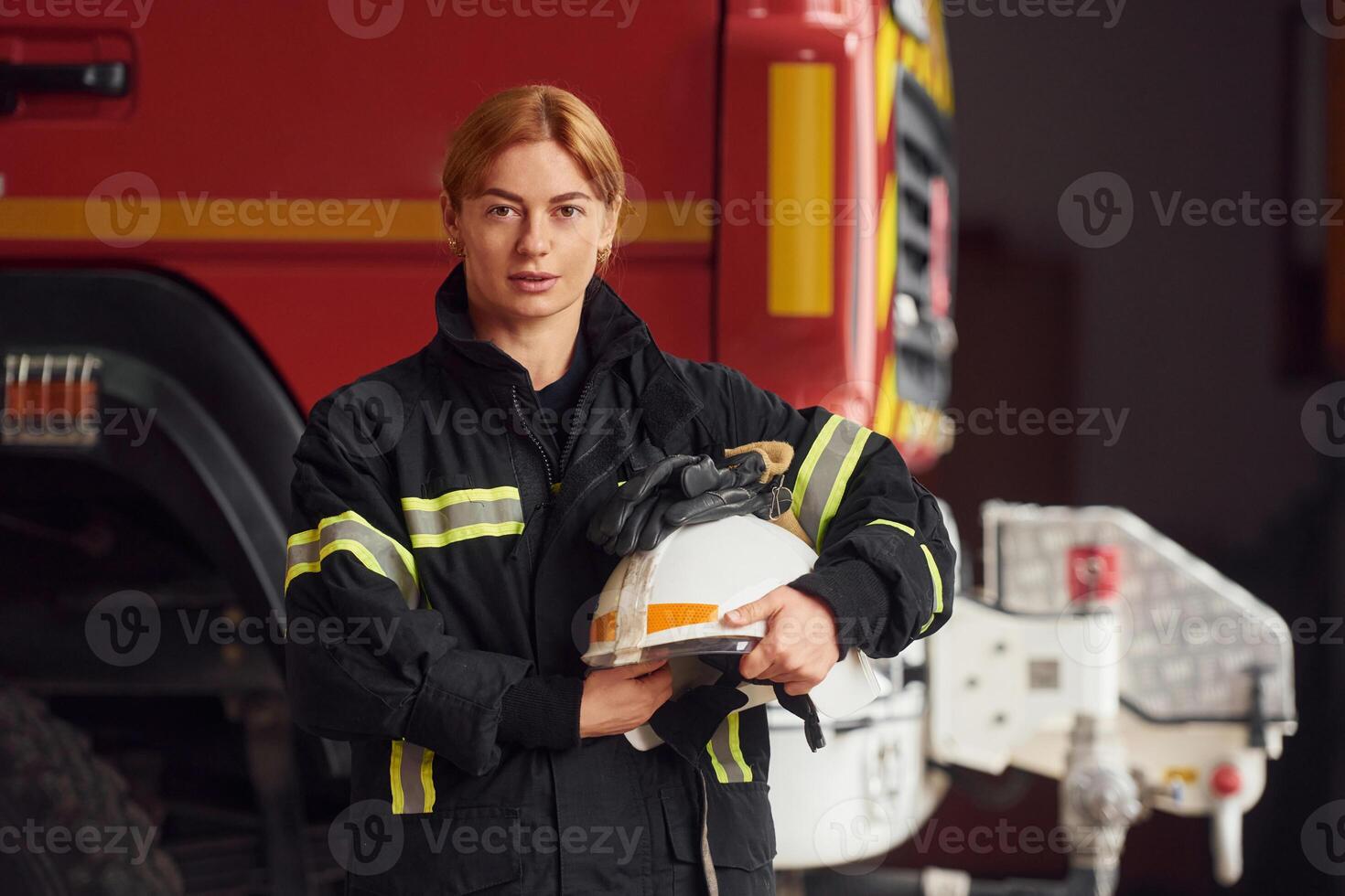 Holding, helmet. Woman firefighter in uniform is at work in department photo