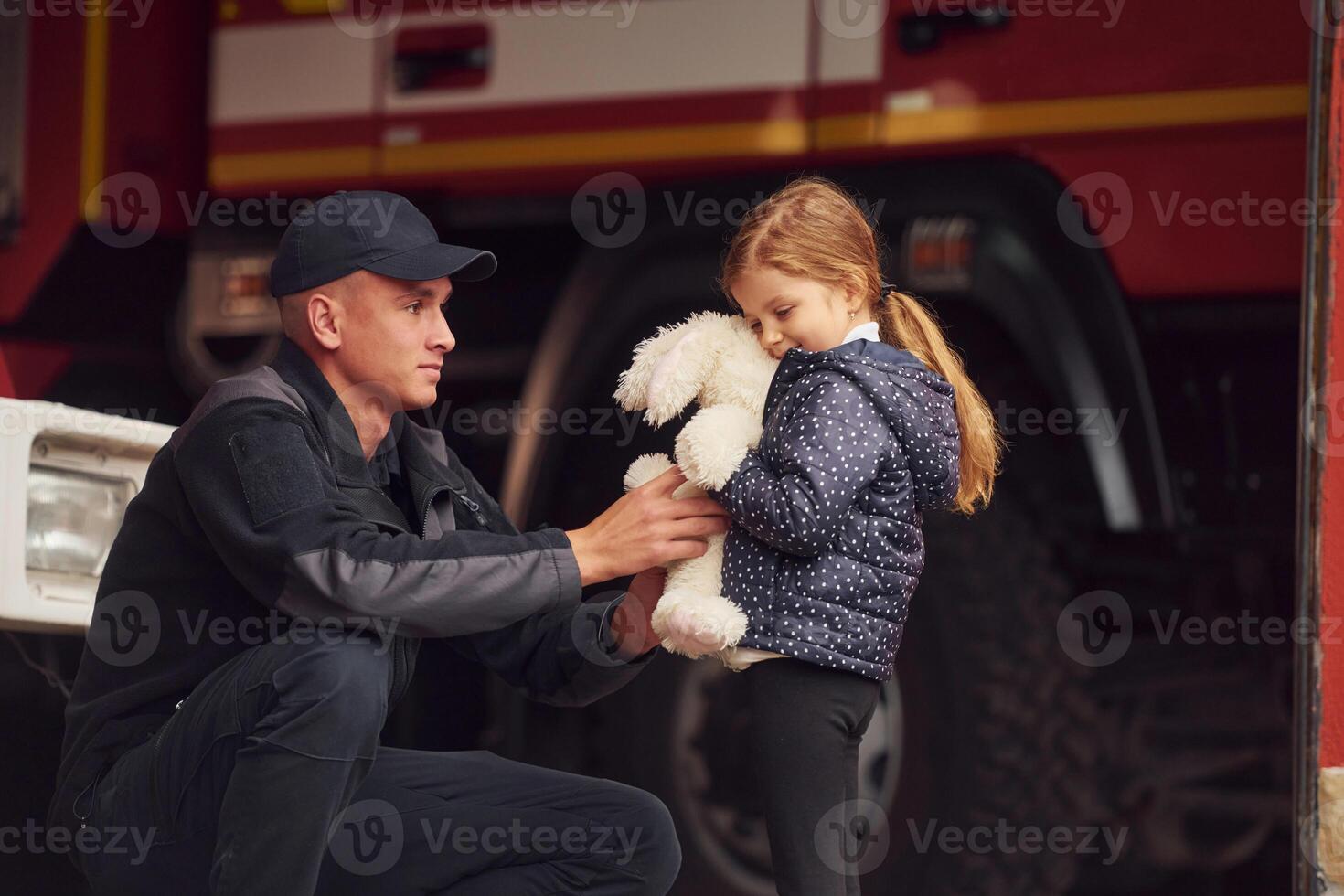 With little ,bunny toy. Firefighter man is with little girl at department photo