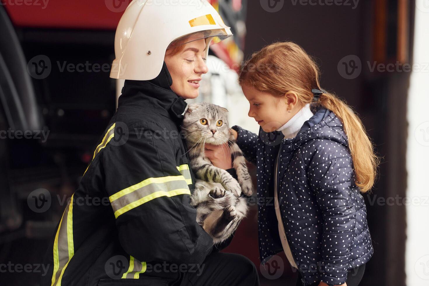 Rescued ,scottish ,fold cat. Firefighter woman in uniform is with a little girl photo