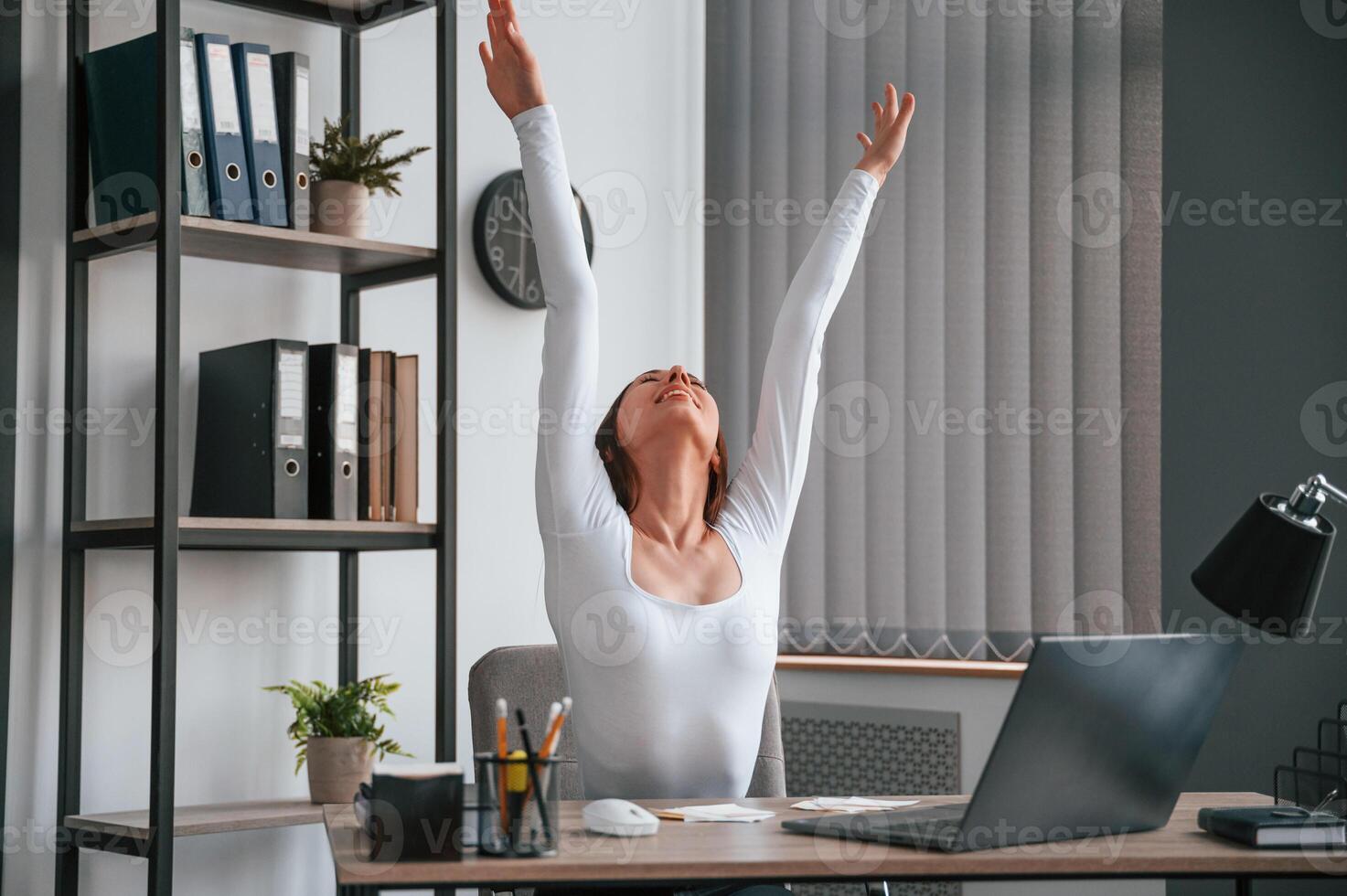 Doing exercise ,break. Young beautiful woman in white clothes is in the office photo