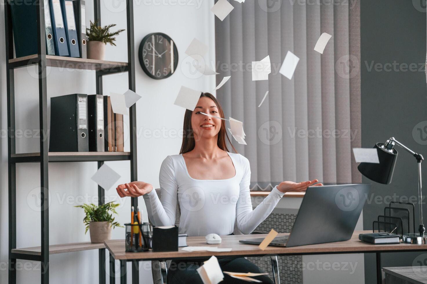 Throwing stickers up into air.. Young beautiful woman in white clothes is in the office photo