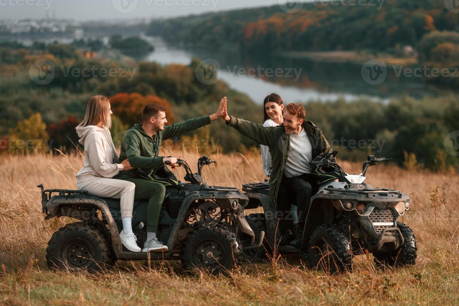 Giving ,high five and smiling. Two young couples with quad bikes is together on the field photo