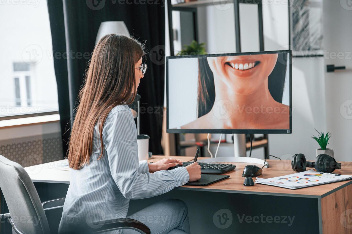 Young female, retoucher working with computer and graphic tablet photo