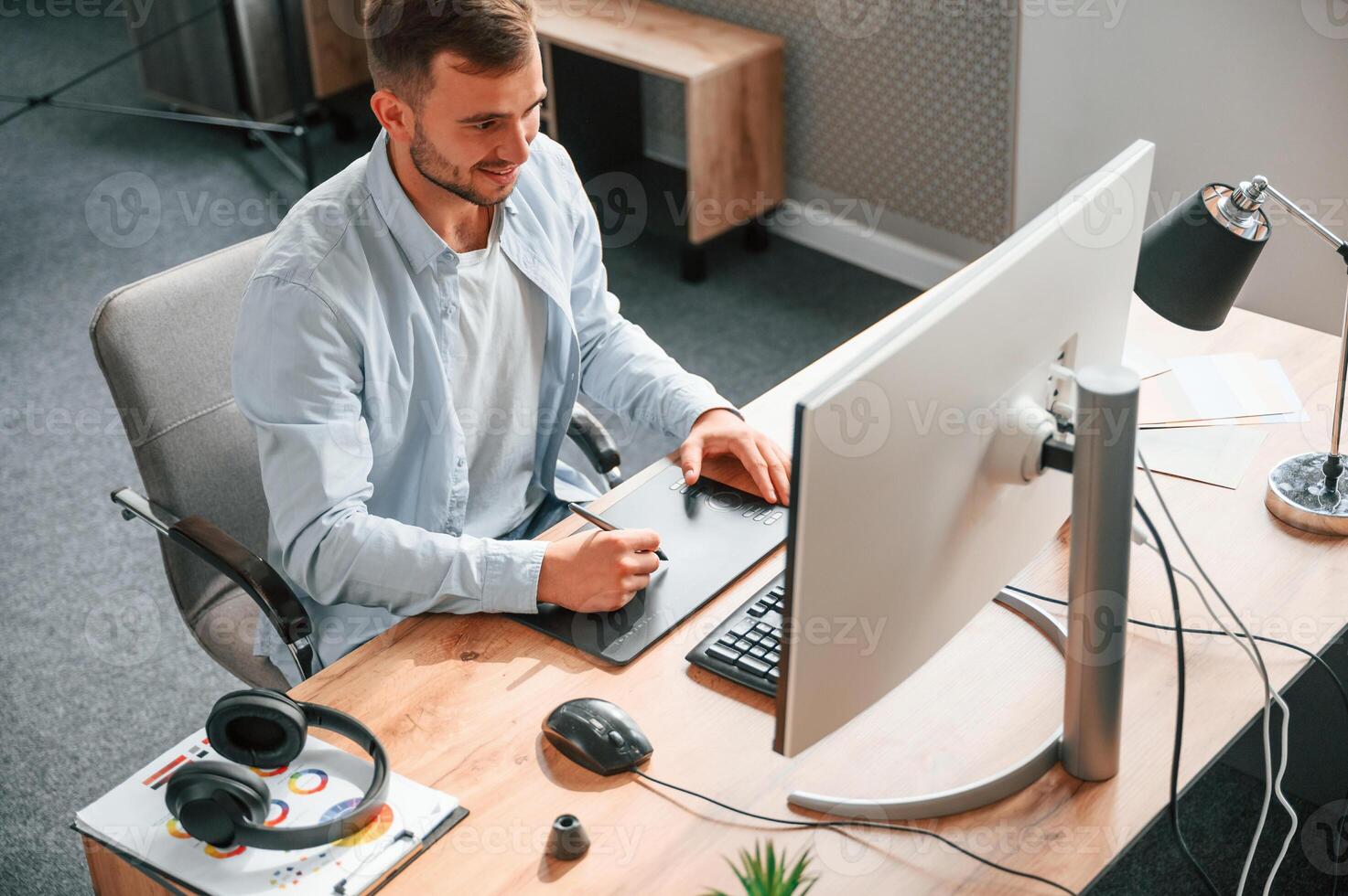 Top, view. Designer is sitting by the computer and using graphics tablet with stylus photo