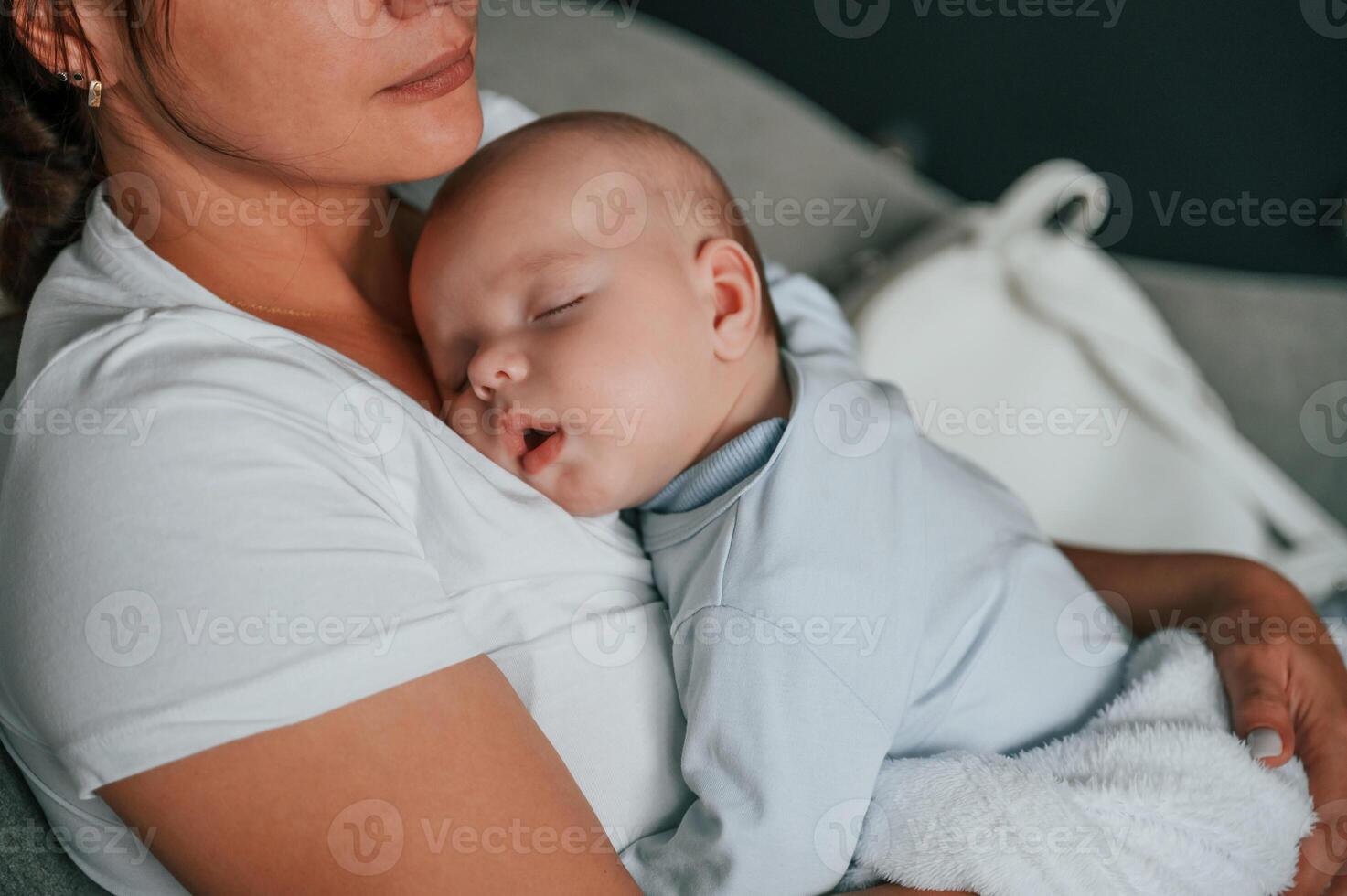 Close up view of cute baby that sleeping on the mother's chest photo