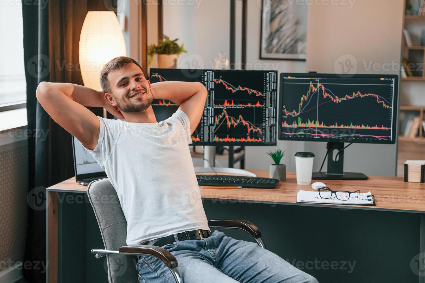 Taking a break.. Young stock broker is working in the office by using computer photo