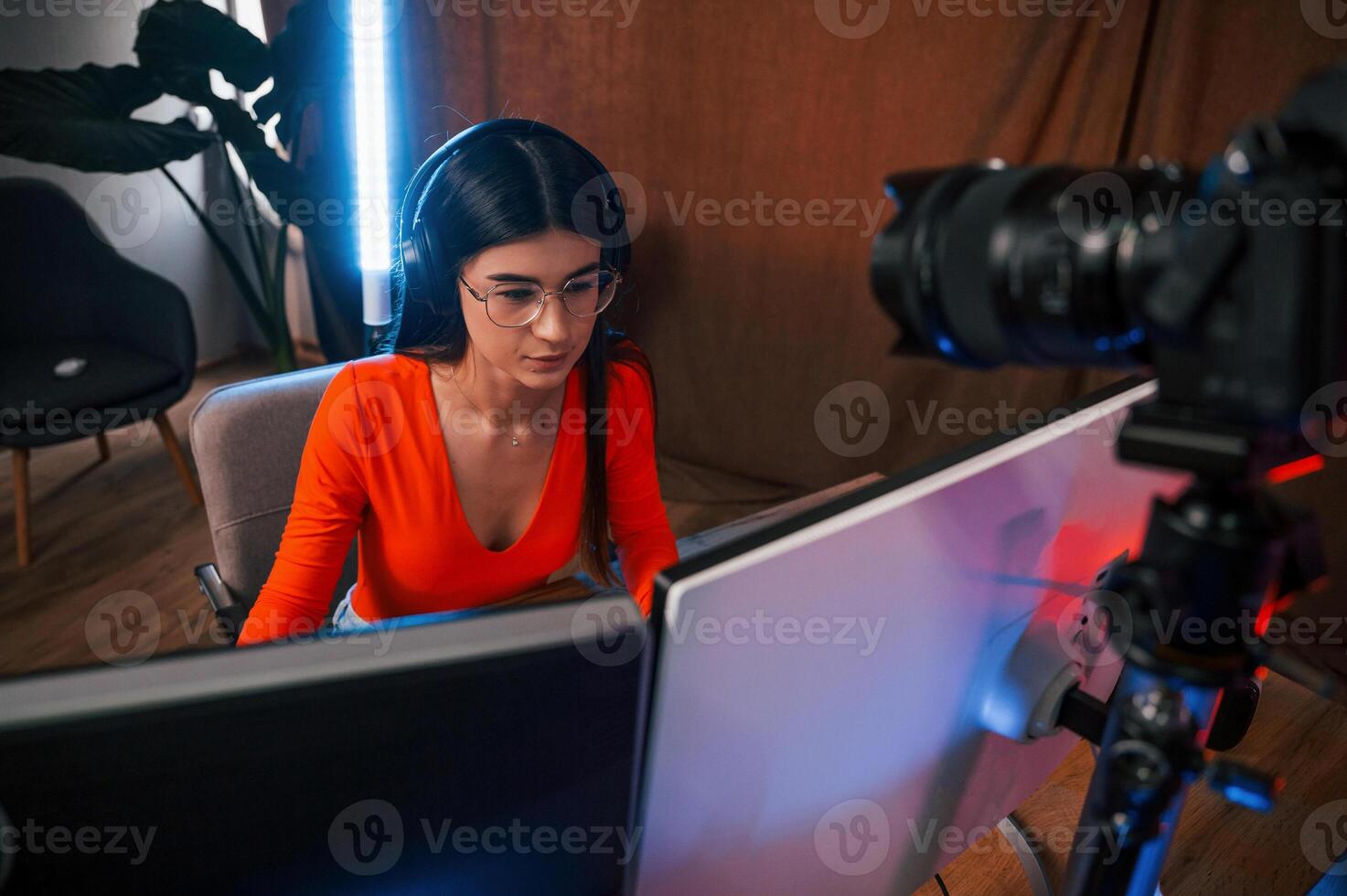 Professional camera is recording the woman. Young beautiful game streamer is indoors with pc photo