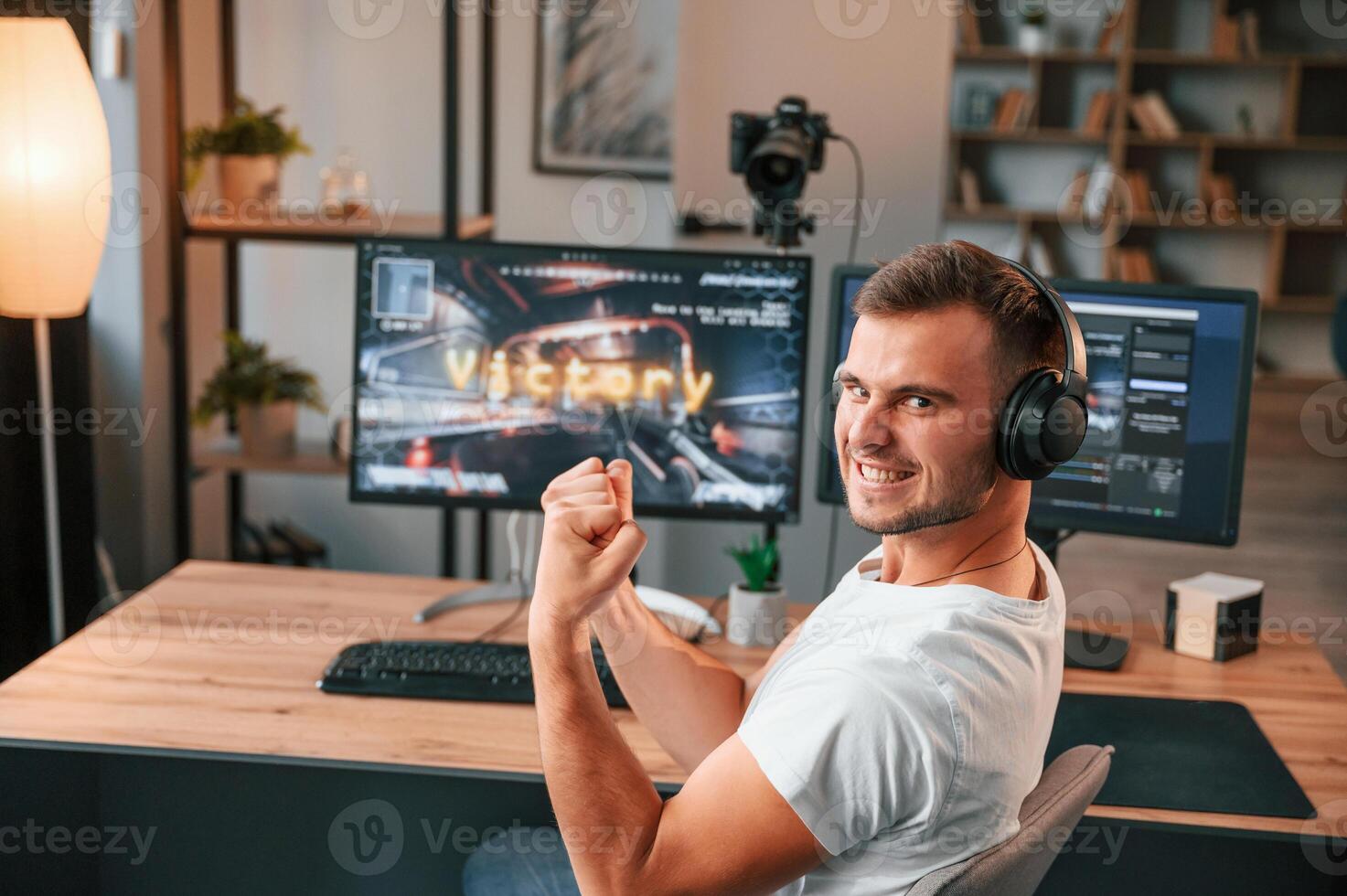 Finally, a victory.. Young man playing and streaming the first person shooter game photo