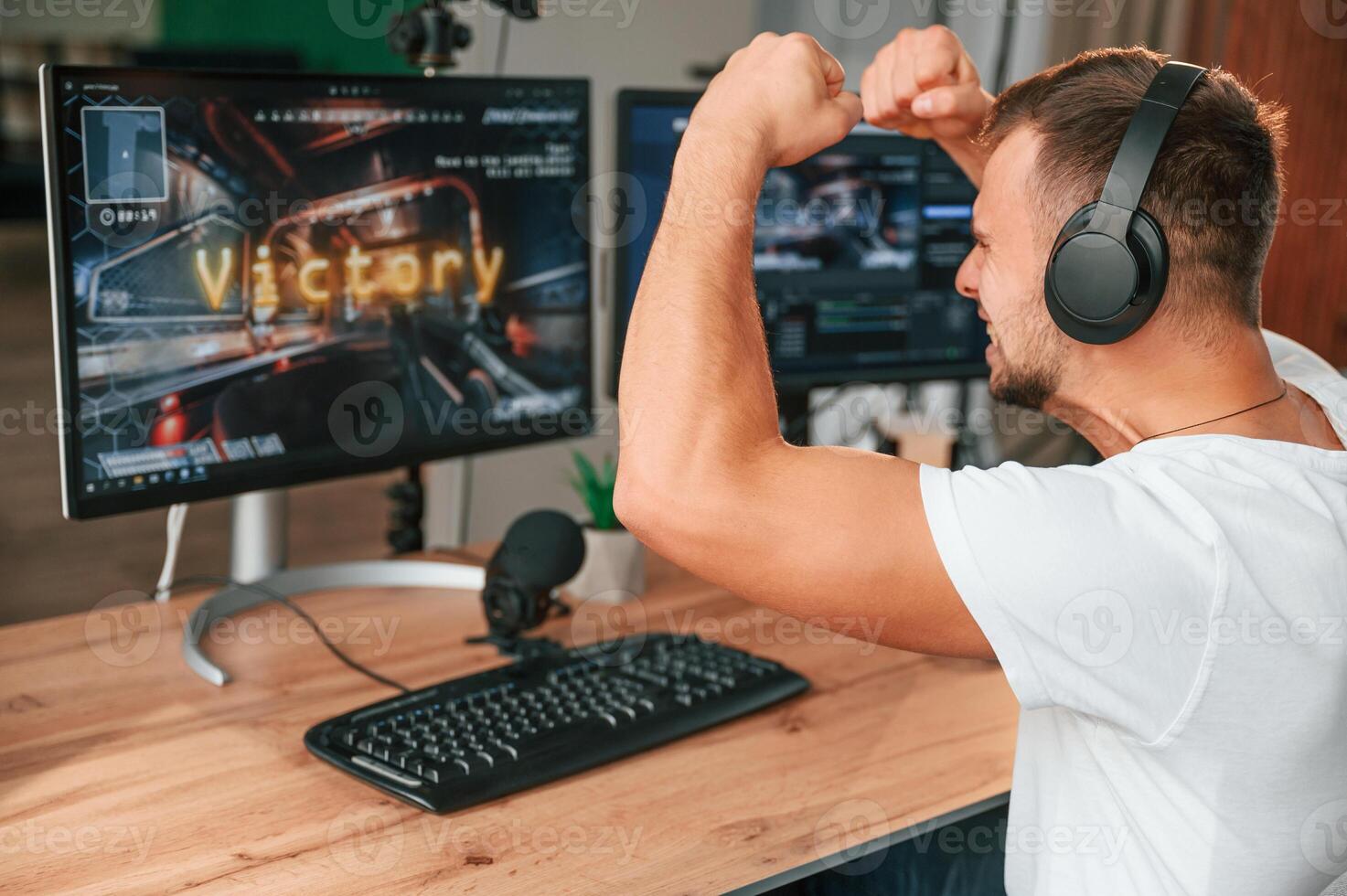 With hands up. Celebrating victory.. Young ,man playing and streaming the first person shooter game photo
