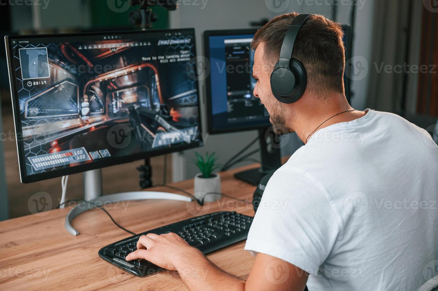 Sitting and focused. Young man playing and streaming the first person shooter game photo